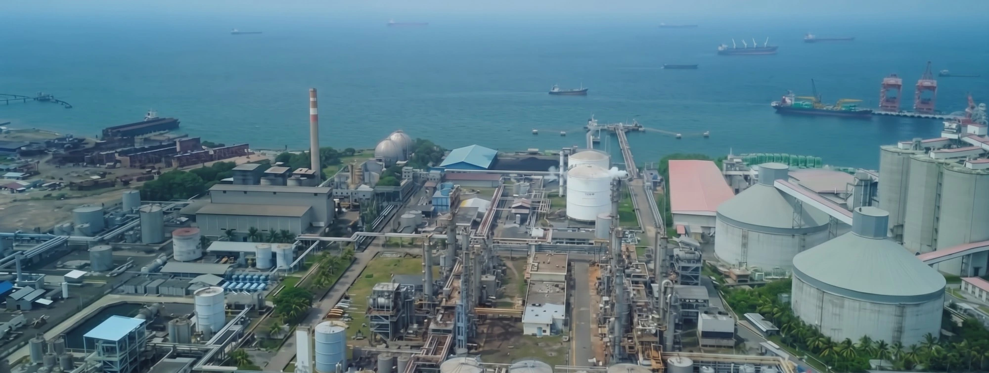 Fasilitas pabrik petrokimia pendukung IndoCoolant di tepi laut, dengan tangki penyimpanan dan dermaga bongkar muat